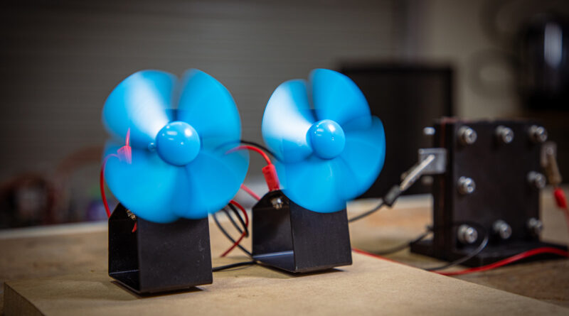 Two blue fans sitting on top of a wooden table.